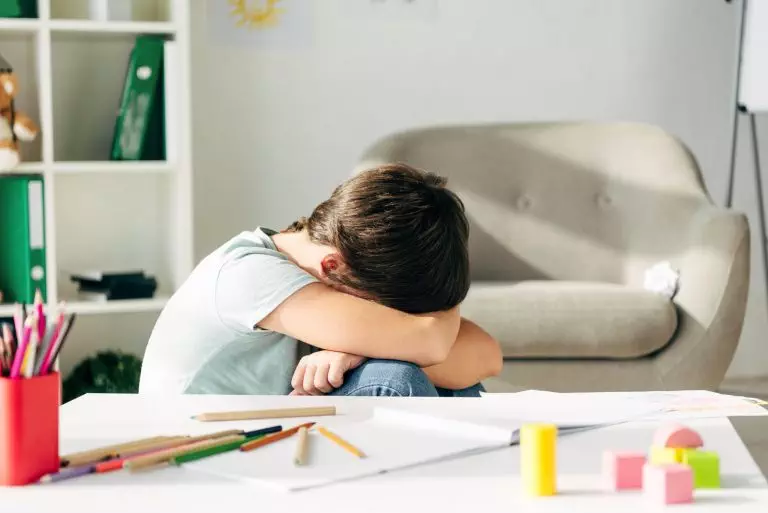 side view of sad kid with dyslexia crying in clinic